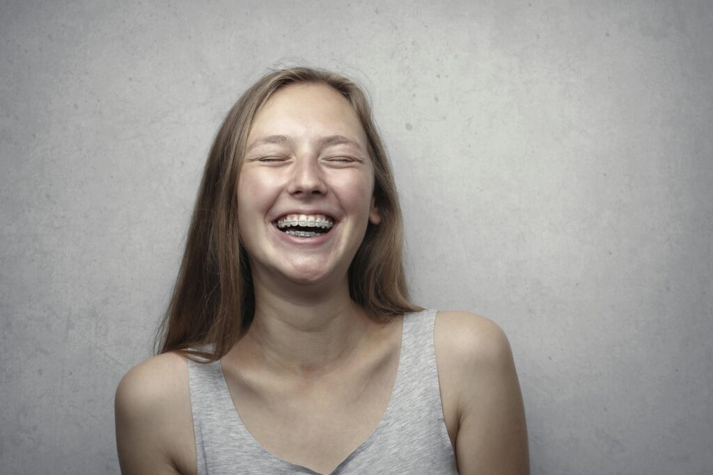 A cheerful woman with braces laughing joyfully in a casual portrait.