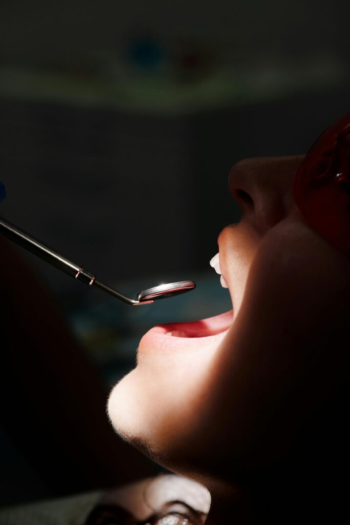 A close-up view of a dental inspection with mouth mirror and light on teeth.