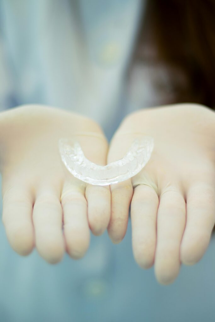 Focused image of gloved hands presenting a transparent dental retainer, emphasizing dental hygiene.